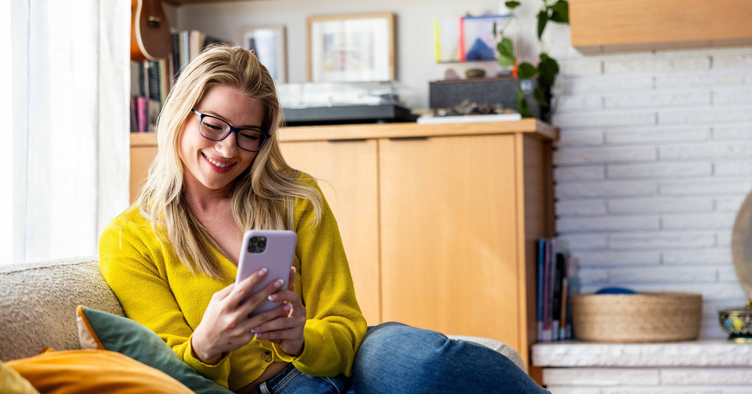 Someone sitting on a couch and ordering glasses on their phone.