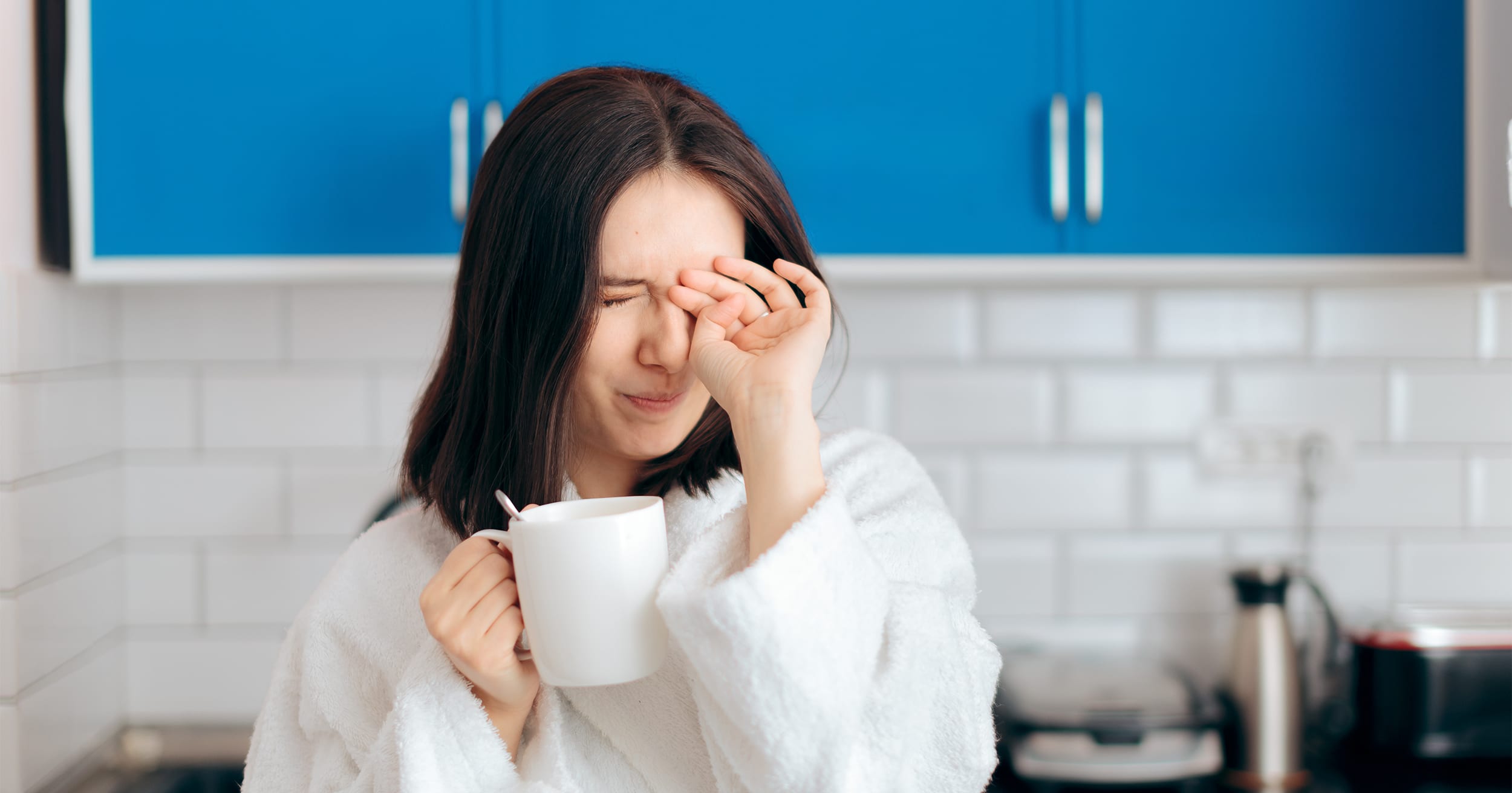 person distressed and tired holding a mug in kitchen